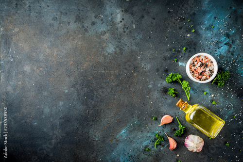 Cooking background with spices, olive oil and herbs, dark blue concrete background, copy space top view