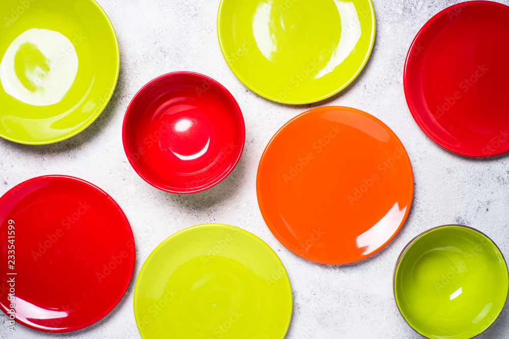 Colored dinnerware - red and green plates on light stone table. Colored dinnerware - red and green plates on light stone table.
