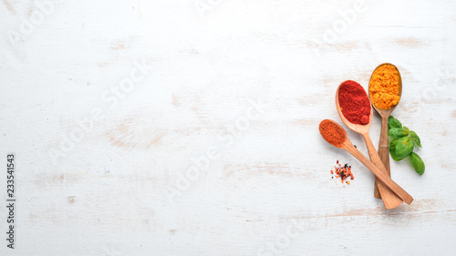 Fototapeta Naklejka Na Ścianę i Meble -  A set of Spices and herbs on a white wooden table. Basil, pepper, saffron, spices. Indian traditional cuisine. Top view. Free copy space.