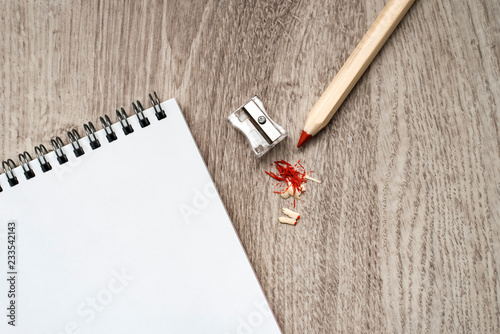 Still life Stationery, supplies for school, office work and creativity, transparent pencil sharpener with a metal blade, a notebook, a pencil on a wooden background.