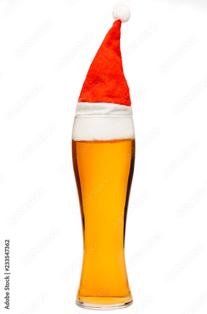 Tall glass of pale ale or beer with christmas red hat isolated on white Tall glass of pale ale or beer with christmas red hat isolated on white