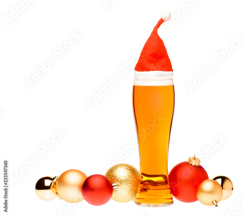 Fototapeta Naklejka Na Ścianę i Meble -  Tall glass of ale or beer with with christmas red hat and baubles on white background