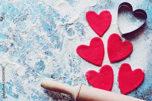 Baking concept for St. Valentines Day with heartshaped cutters and pink cookies on the dark table. Valentines day. Homemade pink heart cookie