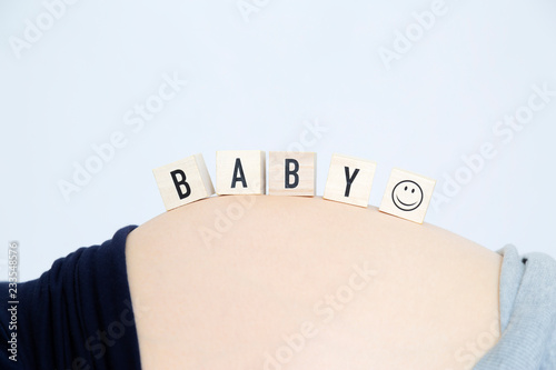 妊娠した大きなお腹の上に並べたメッセージの木製ブロック。妊娠、妊婦、幸せ、愛イメージ