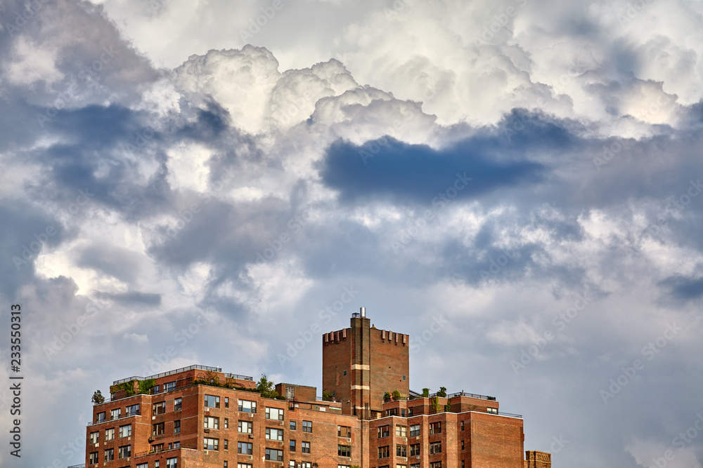 Dramatic cloudscape over an old residential building in New York City, USA.