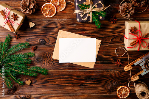 Letter to Santa Claus concept. Top view of composition with christmas gifts and decoration. Vintage toned image with blank wish list for christmason wooden background, flat lay, copy space.