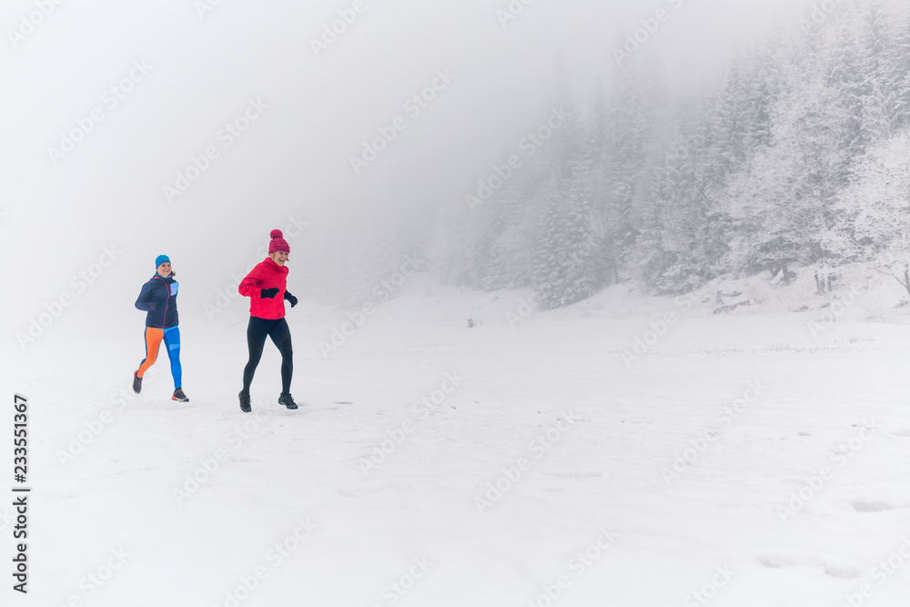 Two women trail running on snow in winter mountains