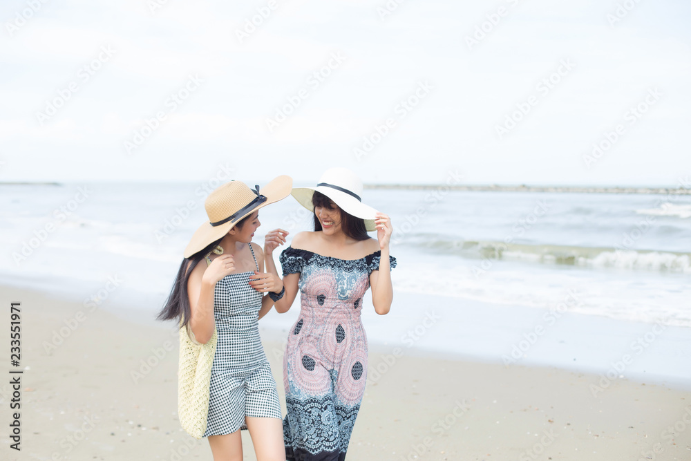 two attractive young asian women walking on the tropical beach