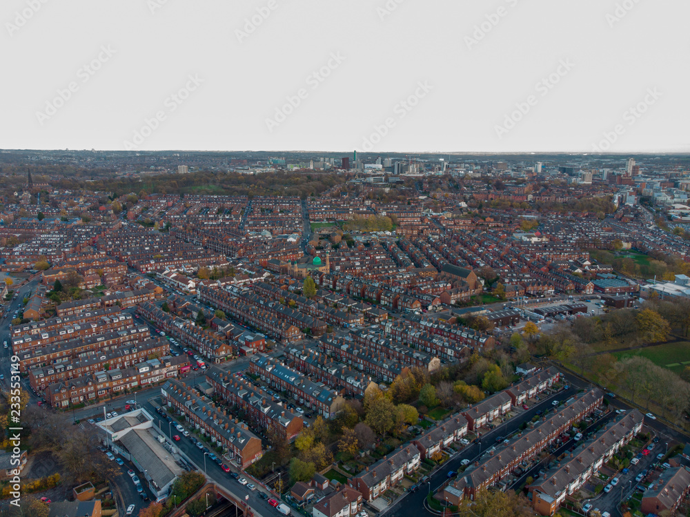 Aerial photo taken above a typical housing estate in the UK showing the tops of the houses on a partly cloudy day.