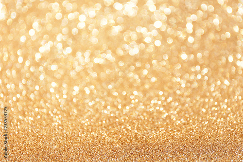 Golden sparkle glitters with bokeh effect and selectieve focus. Festive background with bright gold lights, champagne bubble. Christmas mood concept. Copy space, close up, texture, top view.