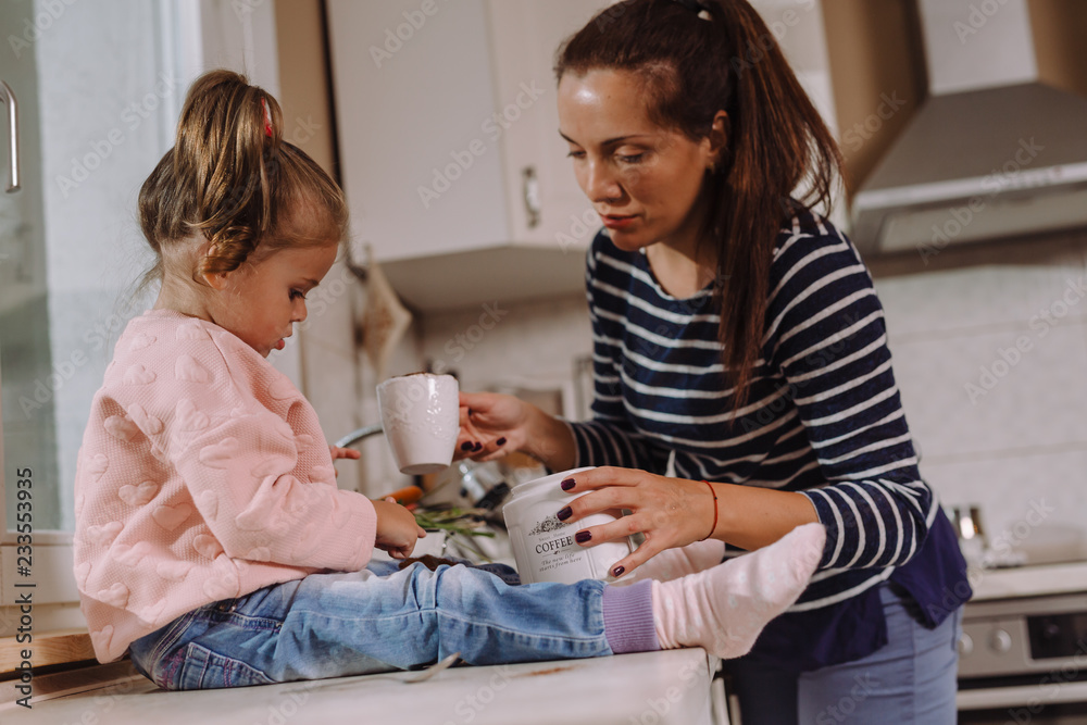 Mother and her daughter drinking coffee in kitchen Mother and her daughter drinking coffee in kitchen