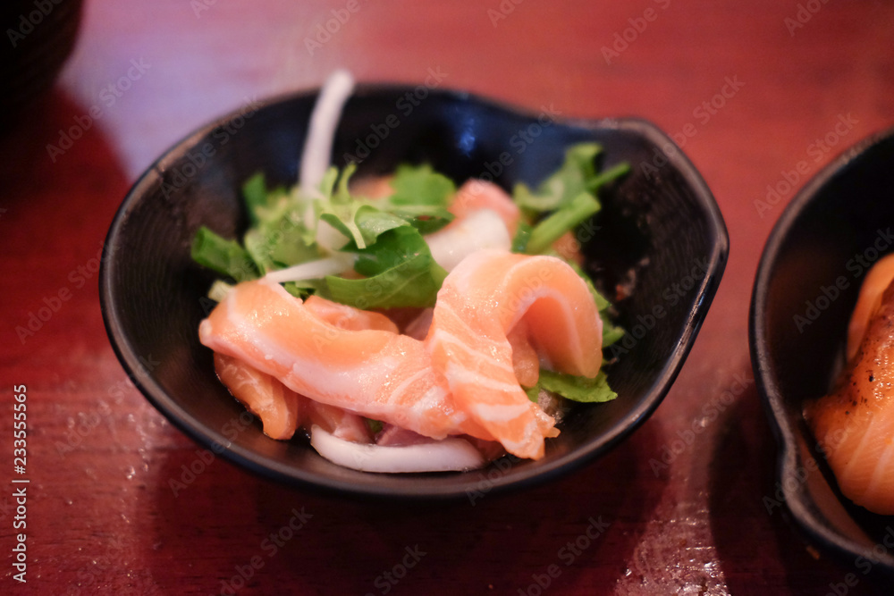 Salmon sashimi spicy salad on black dish