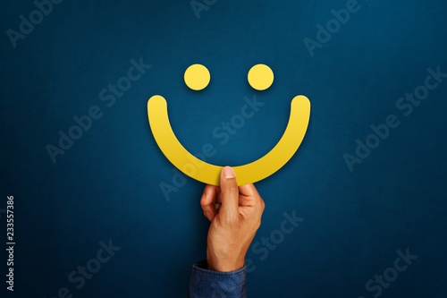 Hand of client show a feedback with smiley face sign. Service rating, satisfaction concept