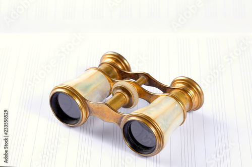 antique theater opera binoculars rest on an empty music score with copy space