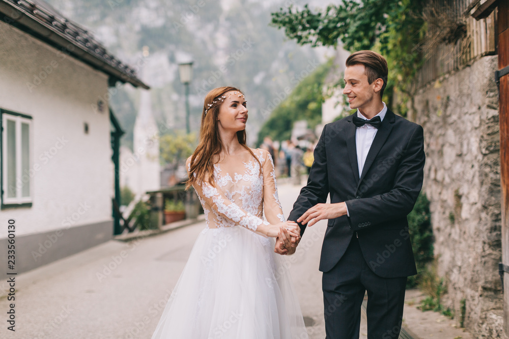 A beautiful wedding couple walks in a fairy Austrian town, Hallstatt.