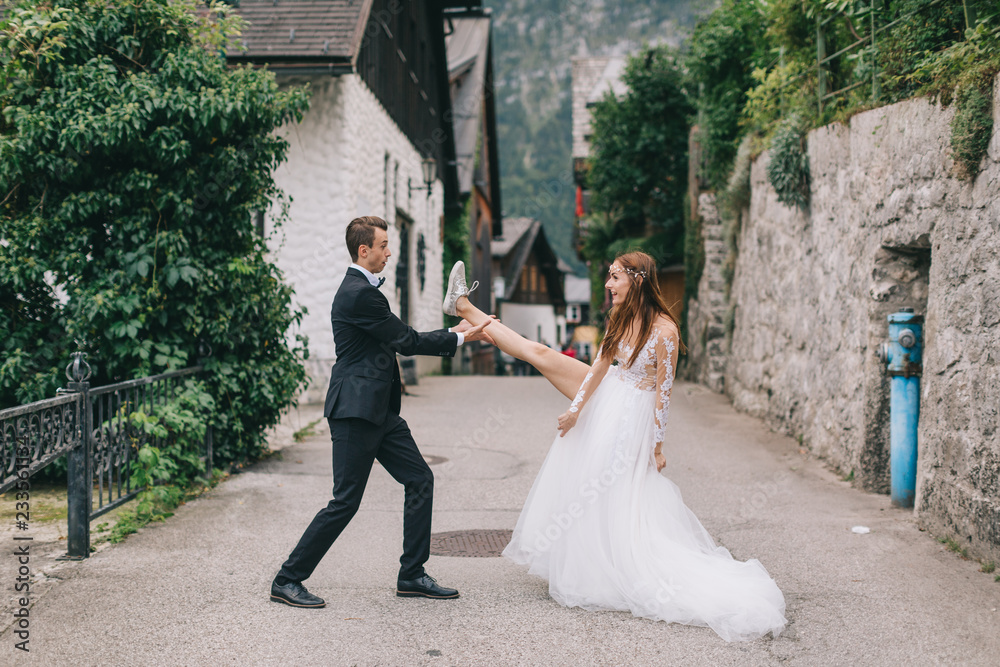A fun wedding couple joking each other and walks in a fairy Austrian town, Hallstatt.