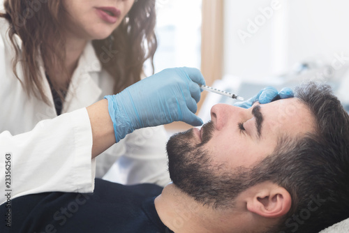 Female doctor putting fillers on man patient