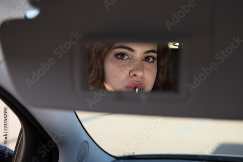 girl putting makeup on the car