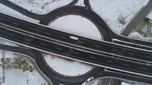 aerial top view of highway with low traffic on snowy winter day