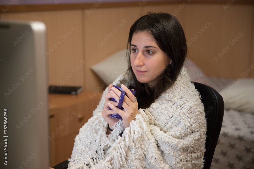 girl in her bedroom watching the computer with a cup and a blanket girl in her bedroom watching the computer with a cup and a blanket