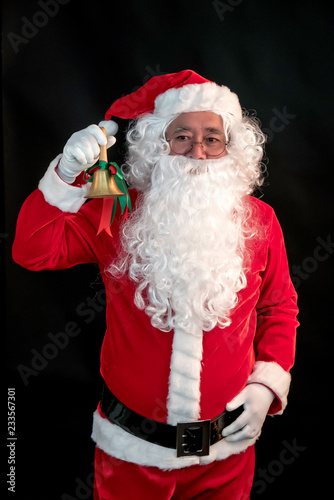 Santa Claus ring a bell on his lift hand studio shot on black background for family, giving, season, Christmas, holiday, new year, travel and gathering concept