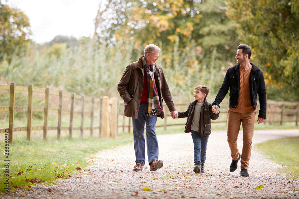 Grandfather With Son And Grandson On Autumn Walk In Countryside Together