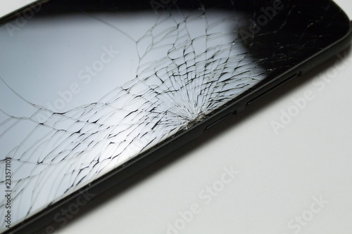 Accidentally cracked, damaged smartphone LCD screen on white background