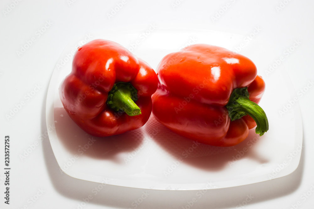 Two red bell peppers lie on a white plate