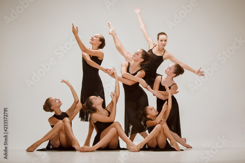 Grupa współczesnych tancerzy baletowych tańczących na szarym tle studio