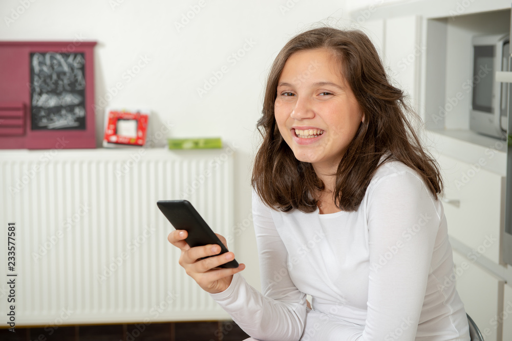 smiling teenage girl texting with smartphone at home smiling teenage girl texting with smartphone at home