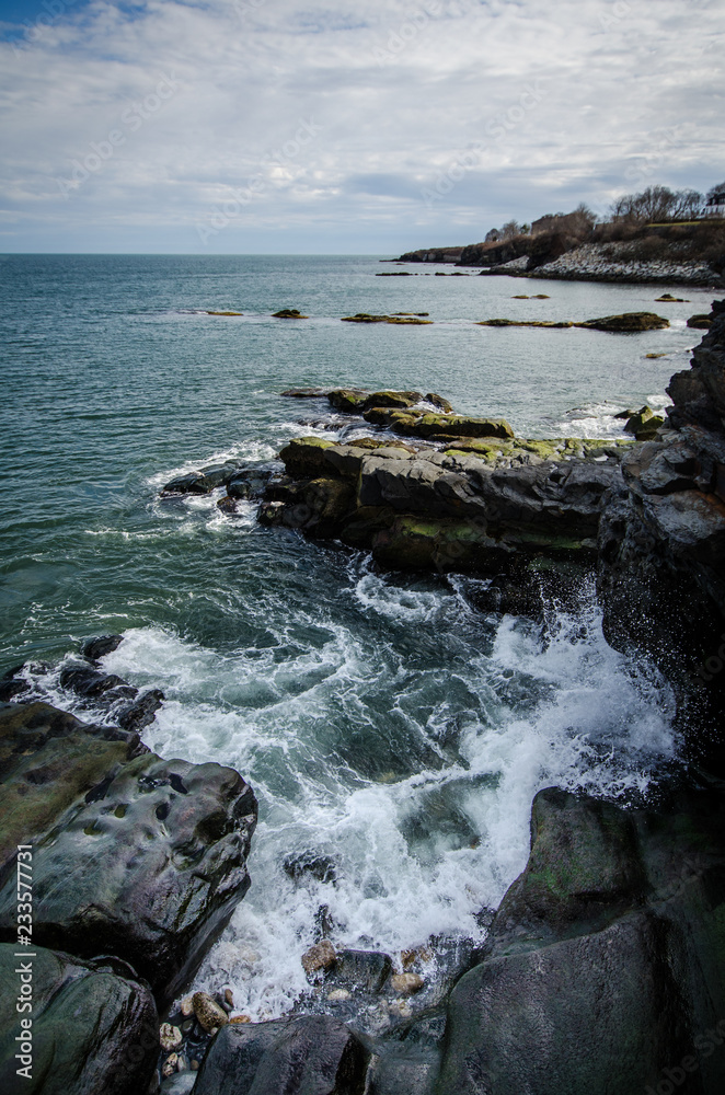 Rhode Island Cliff Walk shows breaking waves along the rocky shoreline of the Atlantic Ocean