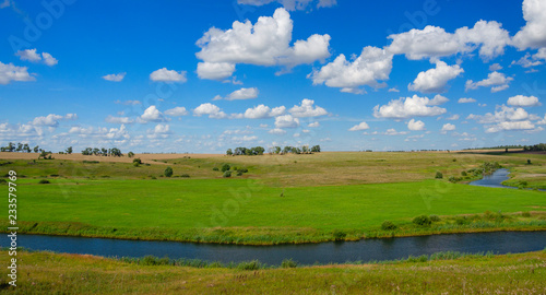 Sunny summer landscape with fields bending river and beautiful woods.