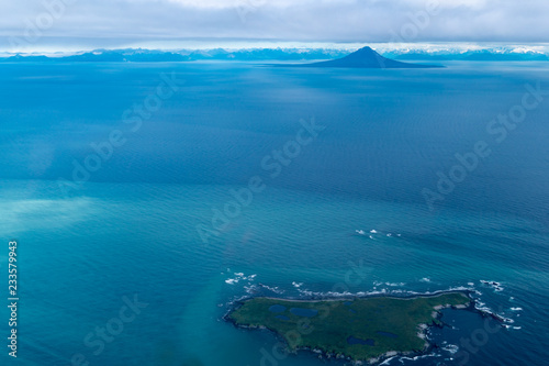 Teal waters of Alaska near Katmai National Park, with view of Augustine Island and the Aleutian Range of mountains. Aerial photography view photo