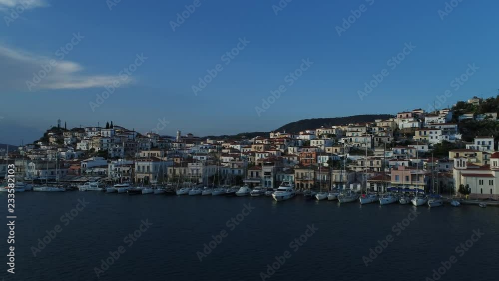 Aerial view. Flying along city promenade and pier with many yachts and boats on the island of Poros, in the evening after sunset. Aerial view. Flying along city promenade and pier with many yachts and boats on the island of Poros, in the evening after sunset.