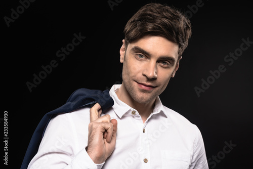 close-up portrait of handsome young businessman in white shirt looking at camera isolated on black