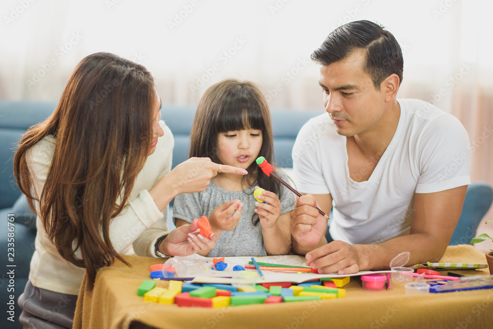 Family time Daughter laughing enjoying playing with her father and mother on the table in front of sofa at home.