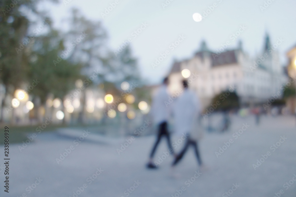 Walking people evening blurry lights background.