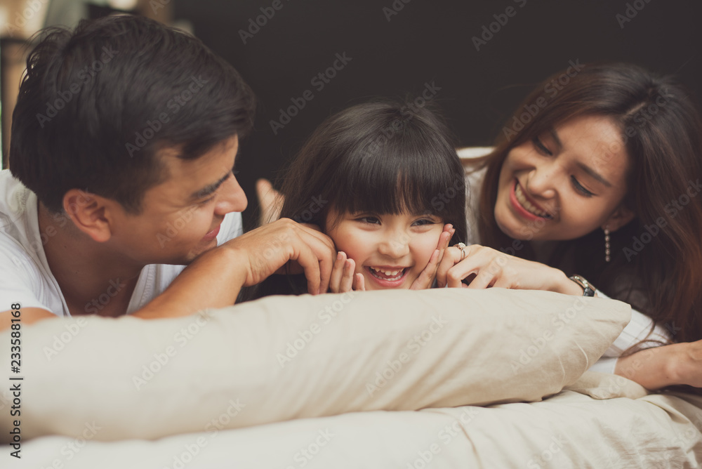 Young mother father and daughter enjoying with lie on the stomach in the bed with pillow, happy family smiling at home. Young mother father and daughter enjoying with lie on the stomach in the bed with pillow, happy family smiling at home.