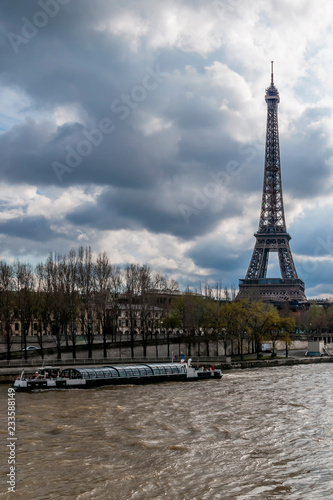 A bateau-mouche on the Seine near the Eiffel Tower on a day with dramatic sky, Paris, France