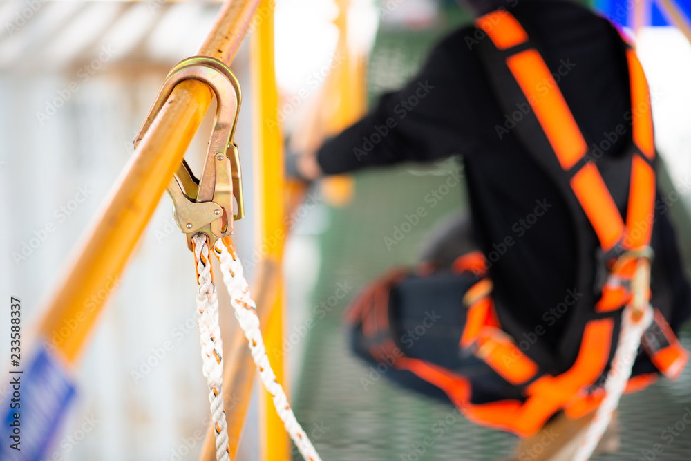 Construction worker wearing safety harness and safety line working on construction Construction worker wearing safety harness and safety line working on construction