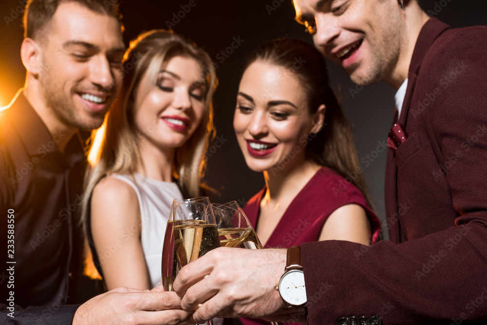 group of friends clinking champagne glasses during party on black group of friends clinking champagne glasses during party on black