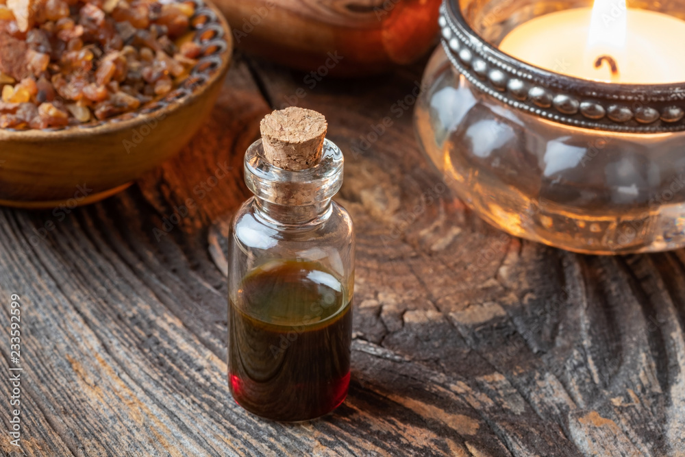A bottle of myrrh essential oil with myrrh resin and a candle A bottle of myrrh essential oil with myrrh resin and a candle