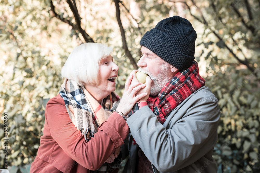 Fototapeta premium Positive bearded man biting a tasty apple