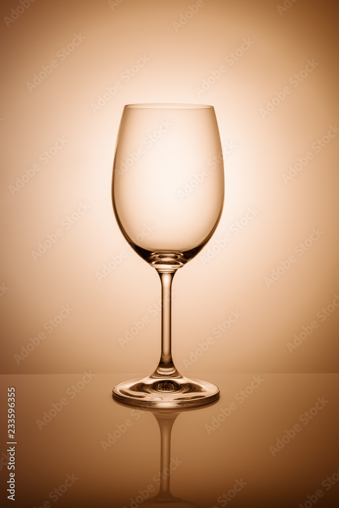 Empty wine glass isolated on the light background toned orange. Empty wine glass isolated on the light background toned orange.