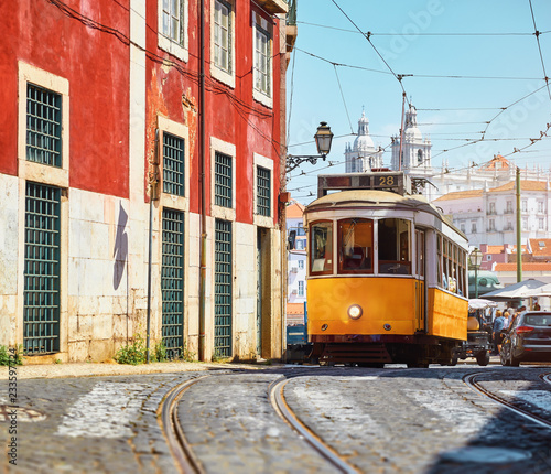 Lisbon, Portugal. Vintage yellow retro tram on narrow bystreet