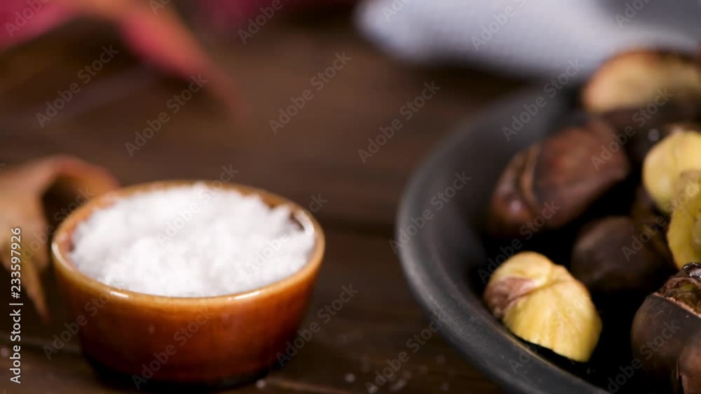Roasted chestnuts in cast iron pan over rustic wooden board and grey wooden background, selective focus. Roasted chestnuts in cast iron pan over rustic wooden board and grey wooden background, selective focus.