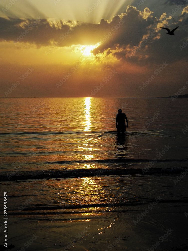 Man bathing in the sea at sunset