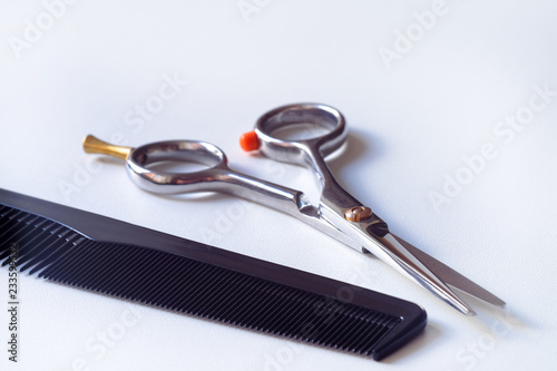 Scissors with finger rest on ring and comb isolated on white background.