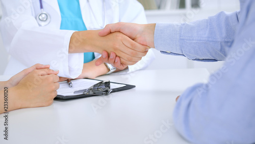 Doctor and patient shaking hands. Family couple at medical exam, just hands at the table. Medicine concept