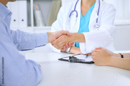 Doctor and patient shaking hands. Family couple at medical exam  just hands at the table. Medicine concept